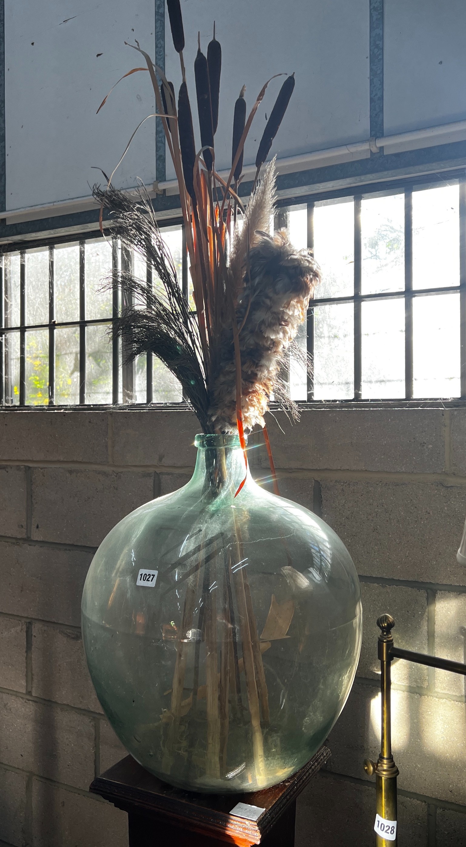 An early 20th century oak pedestal and a green glass carboy, combined height 150cm